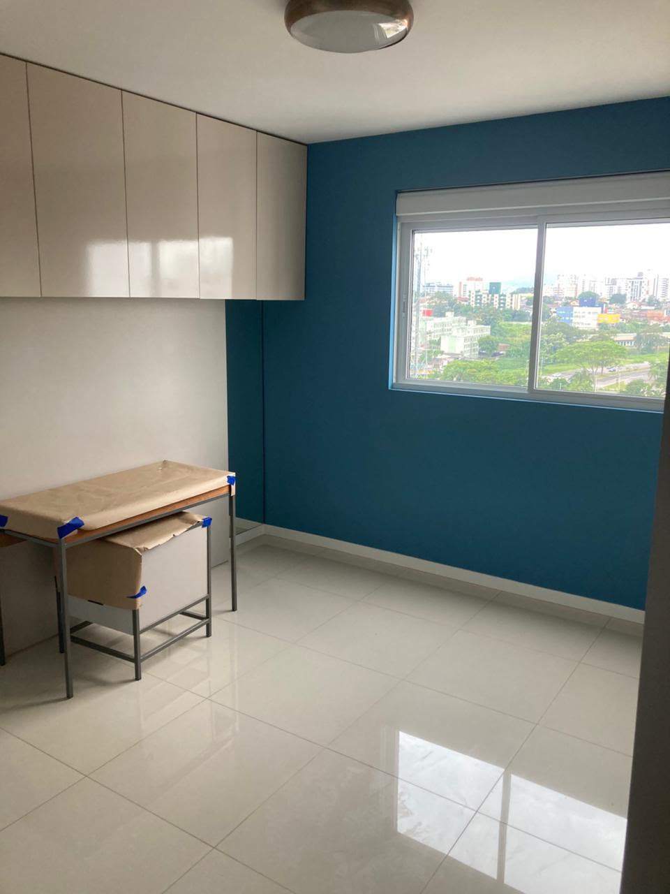 Ambiente residencial com parede em azul e recortes retos junto ao teto e à janela