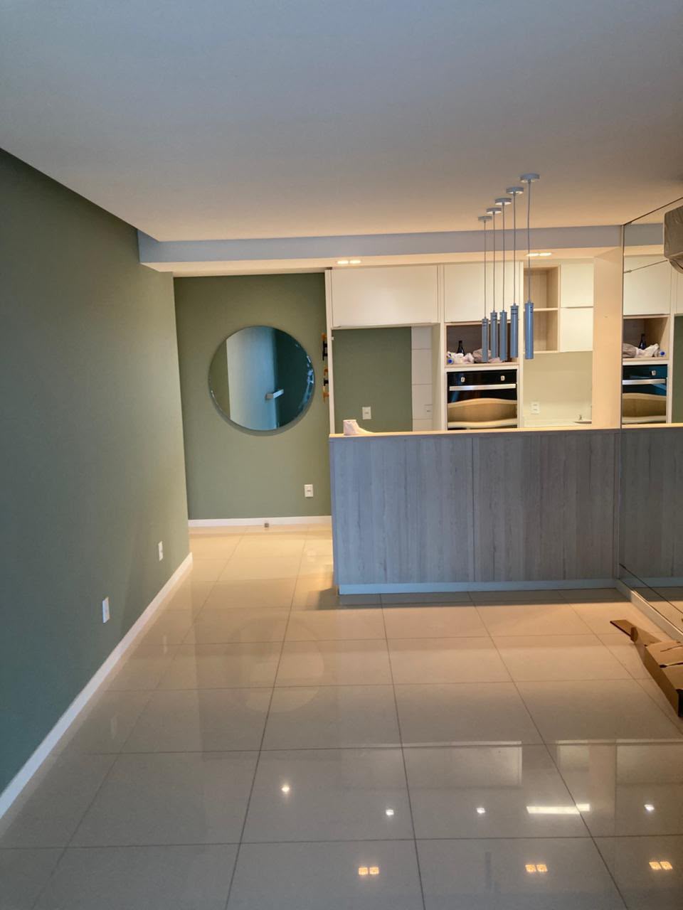 Sala de estar com parede de destaque em verde oliva e demais paredes brancas, acabamento interno