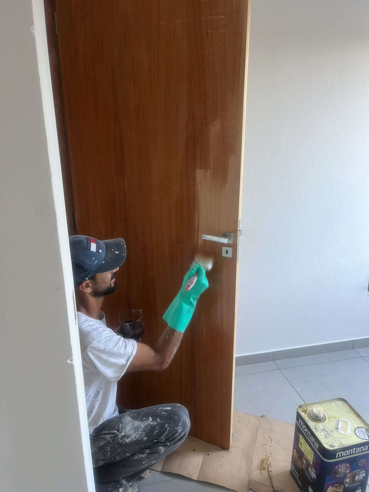 Pintor da 1000&UmaPinturas aplicando verniz em porta de madeira com pincel