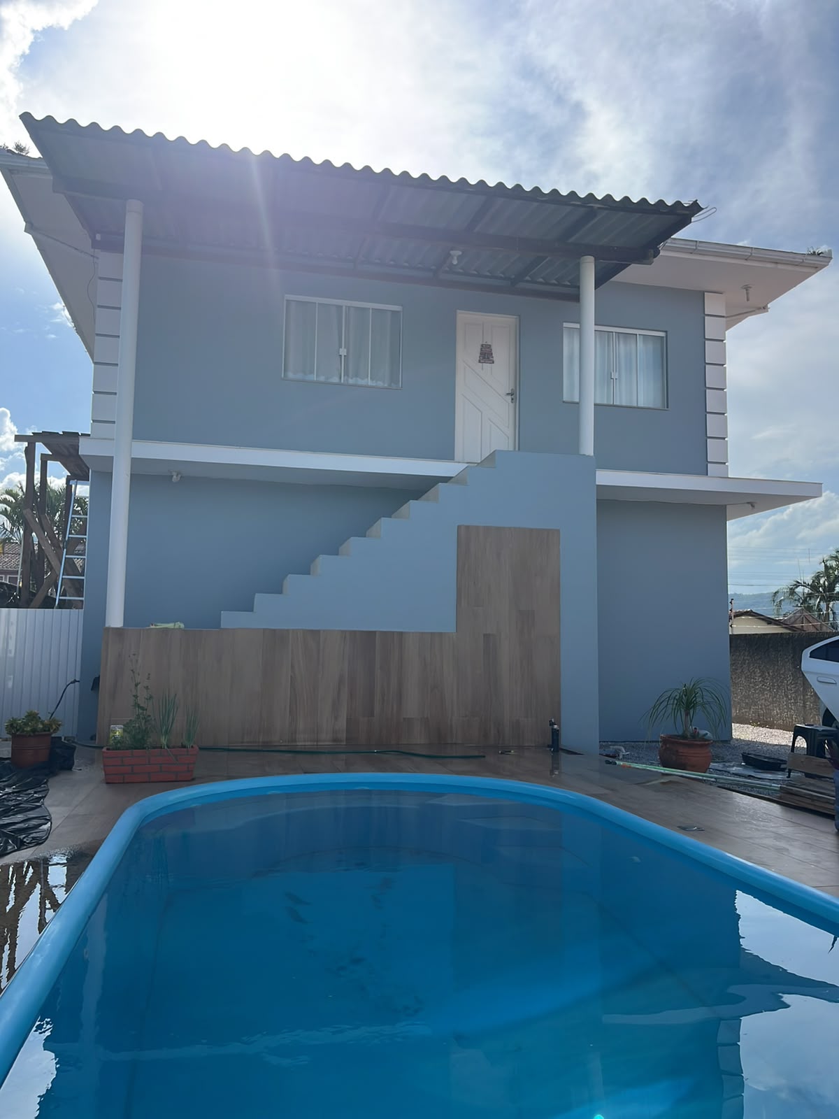 Fachada residencial pintada em azul claro com detalhes brancos, acabamento externo profissional