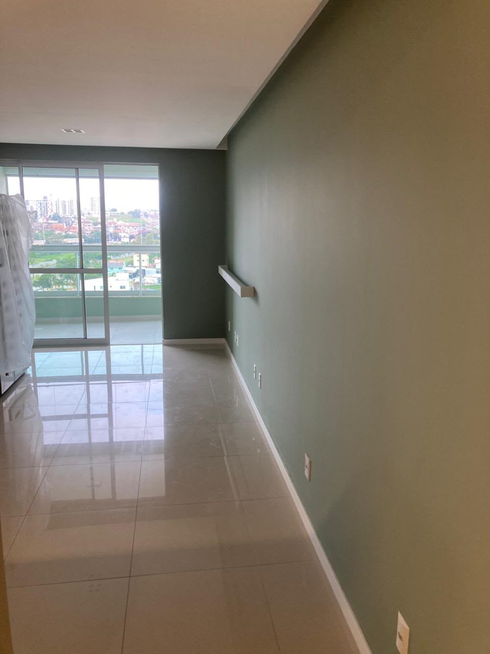 Sala ampla com parede em verde sálvia e acabamento uniforme até o rodapé