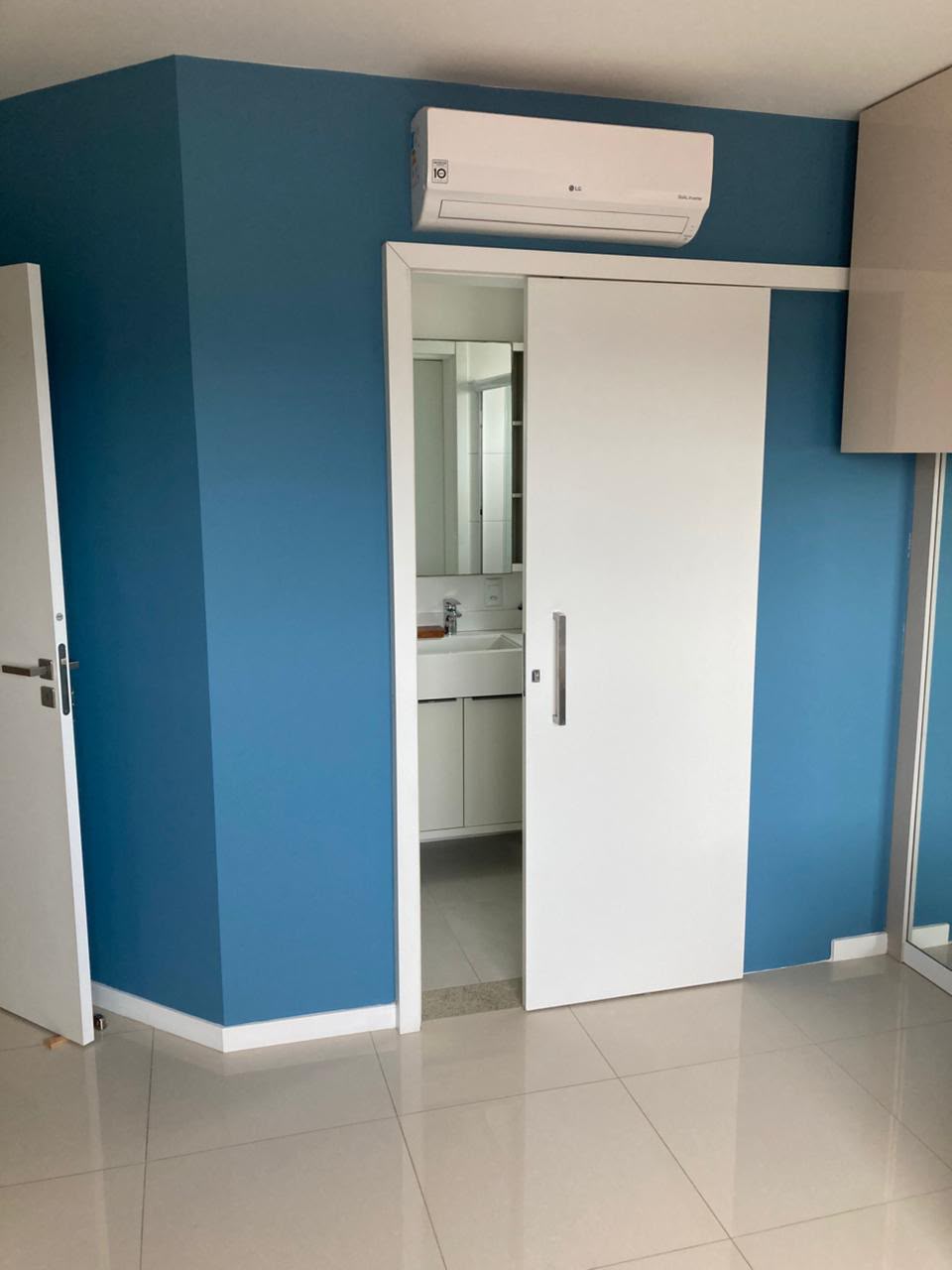 Quarto com parede de destaque em azul profundo e recortes precisos ao redor das portas